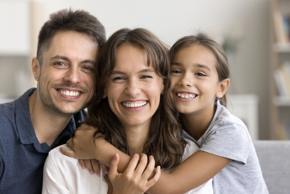 Smiling parents embracing their daughter