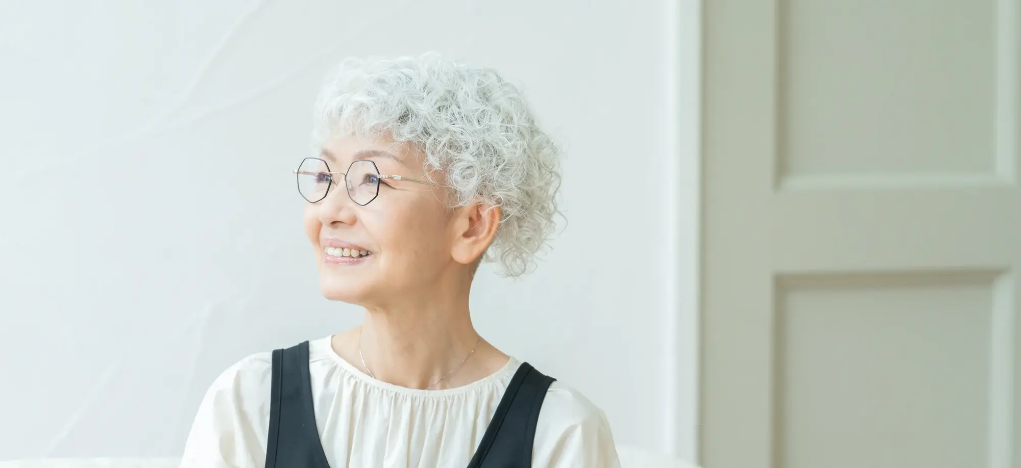 Older woman with short, curly white hair and glasses